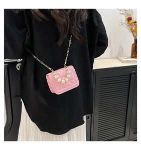 Detailed view of pink heart embossed crossbody bag with pearl handle on model side