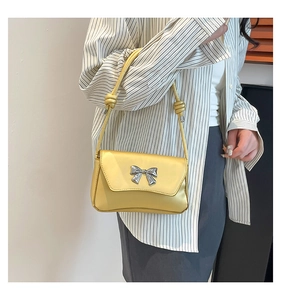 Detailed close-up of a stylish gold crossbody bag with a metallic silver butterfly clasp