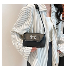 Close-up of minimalist black square shoulder bag with silver metallic bow detail