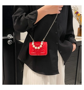 Detail of red heart-embossed mini bag featuring pearl handle and gold chain strap