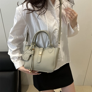 Sage green lychee leather tote bag with gold twist lock and dog charm on a model