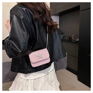 Dettaglio mini borsa a catena rosa glitterata con emblema a stella su giacca di pelle nera