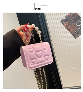 Detail of pink mini handbag with heart stitching, pearl handle, and gold chain strap
