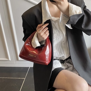 Sac demi-lune bordeaux minimaliste avec lettrage doré porté par le mannequin