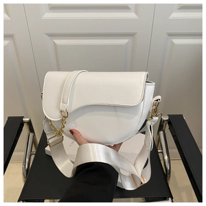 Detailed close-up of a white saddle bag with golden chain and adjustable shoulder strap