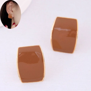 Détail macro de boucles d'oreilles carrées en résine marron avec bordure en métal doré