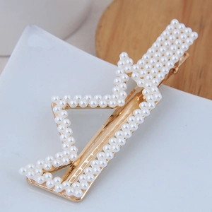 Détail macro de la barrette géométrique en zigzag avec alliage doré et perles blanches
