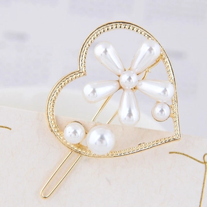Détail de la pince à cheveux perle en forme de cœur avec monture dorée et fleurs