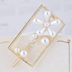 Gros plan d'une barrette dorée rectangulaire avec fleur en perles sur carte blanche