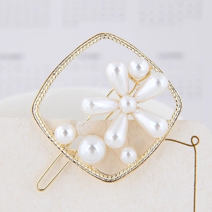 Détail d'une barrette carrée dorée avec fleurs en perles blanches et fermoir en métal