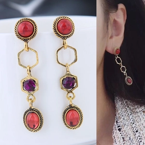 Détail de boucles d'oreilles bohèmes avec pierres rubis et finition en métal doré chic