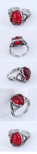 Macro detail of gothic claw ring featuring a large red oval stone and scale textures