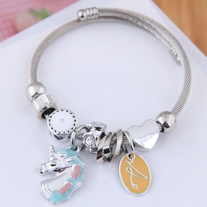 Detailed close-up of a silver unicorn charm bracelet with blue enamel and heart pendant