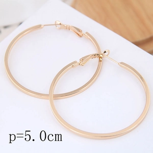 Vue de dessus de boucles d'oreilles créoles dorées de 50mm sur un support de présentation