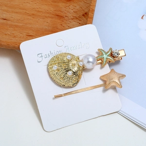 Set di fermagli dorati con conchiglie, stelle marine, perle e strass su carta