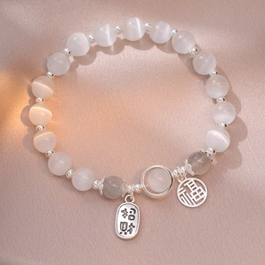 Cat eye stone bracelet with silver Fu and lucky charms on pink silk background