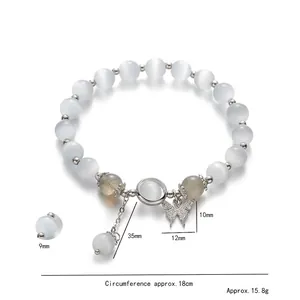 Damesarmband met kattenoogkralen, zilveren vlinderhanger en kwastje als detail