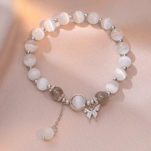 Elegante kralenarmband met witte kattenoogstenen en een sprankelende vlinderhanger