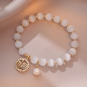 Bracelet en perles d'oeil de chat avec pendentif Fu doré sur un fond en soie élégant