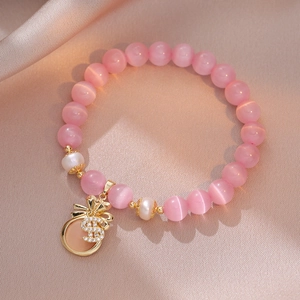 Bracelet en oeil de chat rose avec perles d'eau douce et breloque bourse dorée