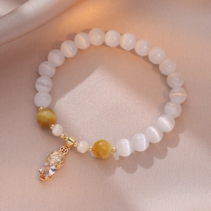 Elegant cat eye stone bead bracelet with golden charm on a champagne silk background