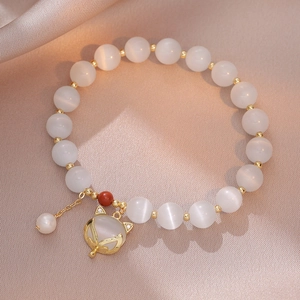 Cat eye stone fox charm bracelet with freshwater pearls on champagne silk background
