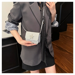 Dettaglio mini borsa argento glitterata con stella di strass indossata da una modella