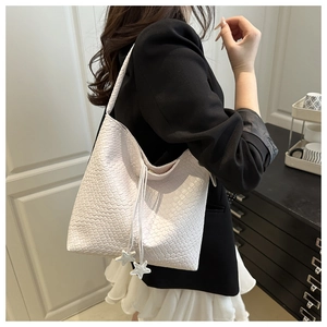 Detail of white woven PU leather hobo tote bag featuring a star charm and drawstring clasp