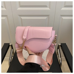 Detailed view of pink saddle bag featuring gold chain hardware and wide nylon strap