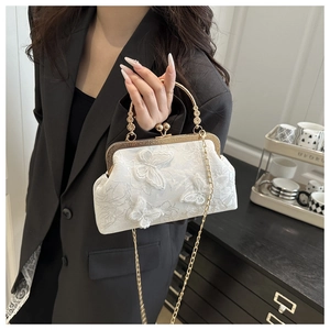 Detailed view of white lace handbag with 3D butterfly appliques and gold metal handle