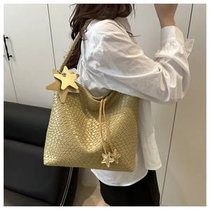 Detailed texture of gold woven hobo bag with star charm and braided shoulder strap