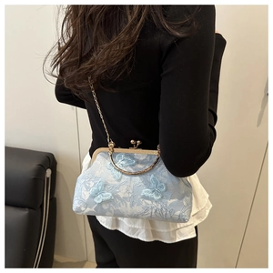 Detail of light blue lace handbag with 3D butterfly embroidery and gold chain strap