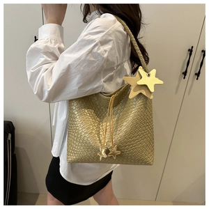 Détail d'un sac cabas tissé doré doté d'un pendentif en forme d'étoile sur la bandoulière