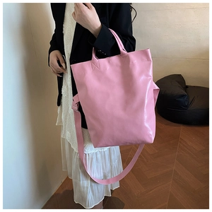 Detail view of large pink glossy leather tote bag with shoulder strap and short handles