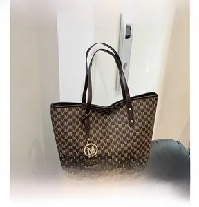 Detailed view of brown letter-print tote bag with gold logo charm on leather seat