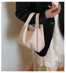 Detail of light pink pebble leather bucket bag with top handles and matching inner pouch