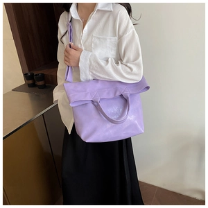 Detail of purple faux leather tote bag showing adjustable strap and soft folding texture