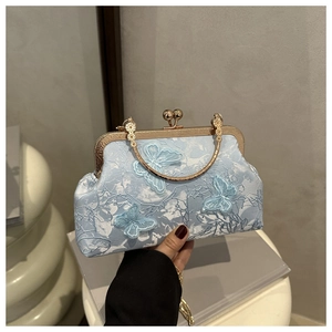 Detail of vintage blue jacquard clutch with butterfly embroidery and golden chain handle