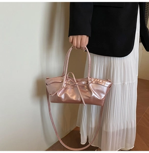 Close-up of pink metallic handbag with bow detail and thin handle in high gloss finish