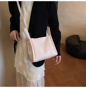 Detail of light beige bucket bag with lychee texture and gold metal buckle on shoulder strap