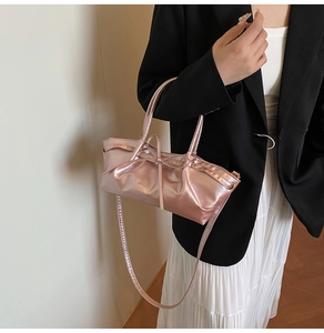 Detail of rose gold metallic handbag featuring pleated design and bow decoration