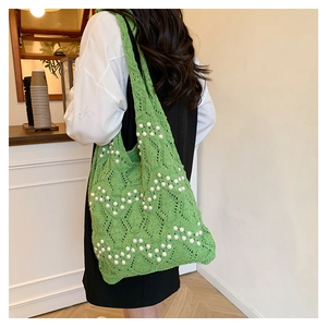 Detail of green hollow knit tote bag featuring intricate white pearl embellishments