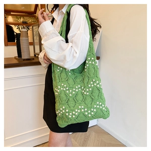 Detail of green knitted tote bag with white pearl accents and wave texture pattern