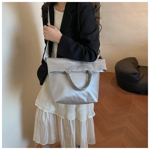 Lifestyle shot of large silver faux leather tote bag being carried as a stylish crossbody bag