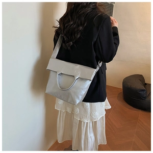 Chic silver metallic tote bag shown on a model in a minimalist stylish indoor setting