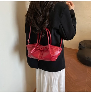 Red ruched dumpling bag with bow detail shown on shoulder for sizing and fit