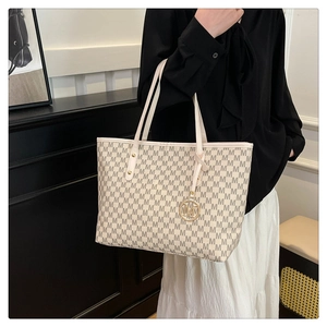 Detailed shot of tote bag featuring M-letter pattern and gold-tone metal logo pendant