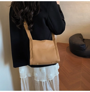 Detail of camel leather handbag showing gold protective feet and pebbled texture