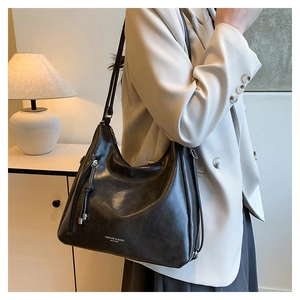 Detailed view of black Hobo tote bag side zipper with fringe tassel on soft leather