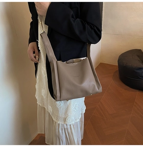 Detail of light brown lychee grain leather bucket bag with gold-tone bottom studs
